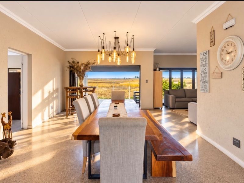 Spacious open-plan dining area featuring polished concrete floors, modern pendant lighting, and large sliding doors opening to scenic landscape views.