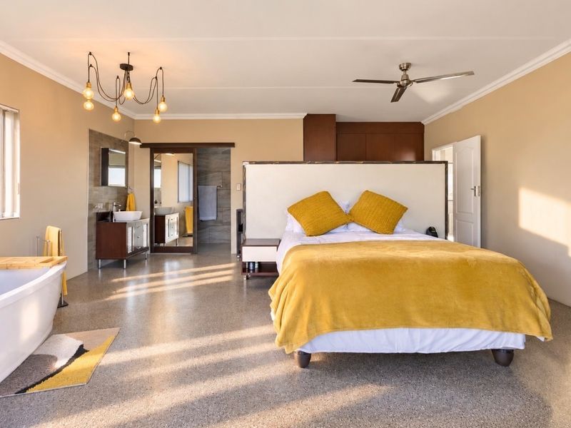 Spacious bedroom featuring an open-plan ensuite with a freestanding bathtub, modern vanity, built-in cabinetry, and polished terrazzo flooring.