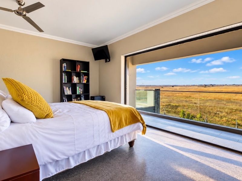 Spacious bedroom featuring a ceiling fan and large sliding glass doors opening onto a balcony with expansive natural landscape views.