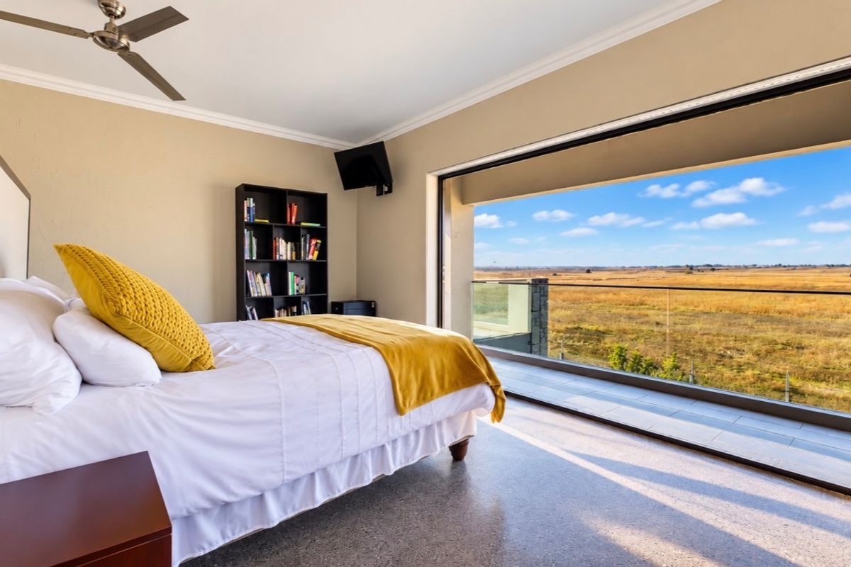 Spacious bedroom featuring a ceiling fan and large sliding glass doors opening onto a balcony with expansive natural landscape views.