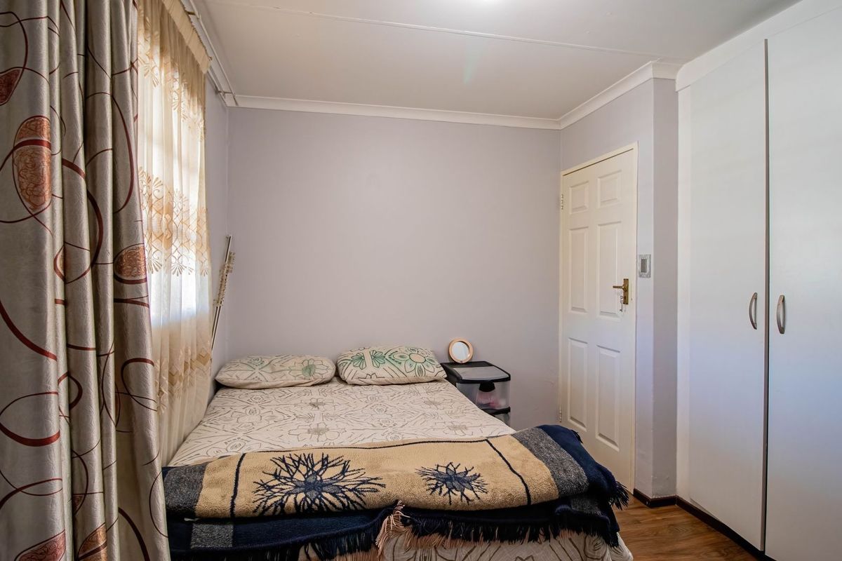 A compact bedroom featuring laminate flooring, a built-in wardrobe, and coved ceiling detailing.