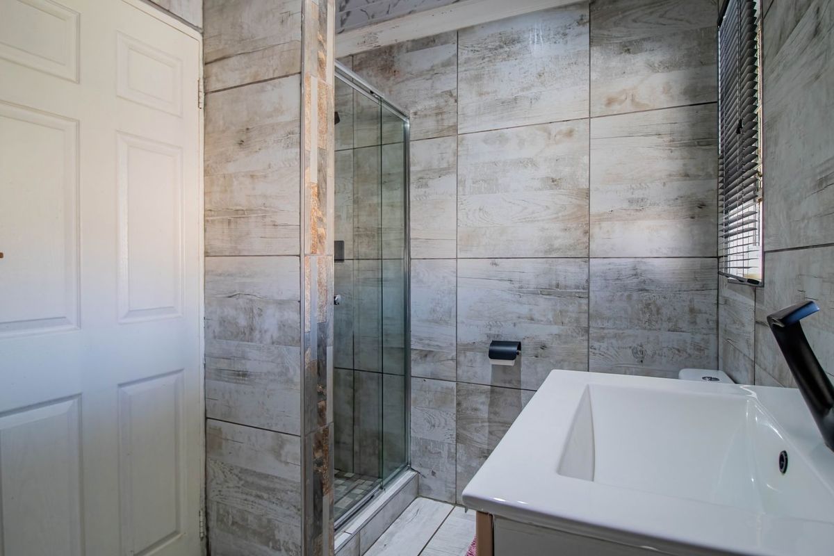 A modern bathroom featuring wood-look tiled walls, a glass-enclosed shower, and a contemporary vanity basin with a sleek mixer tap.