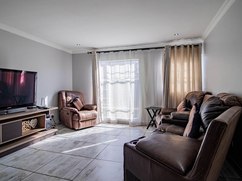 A bright living room featuring large format tiled flooring, recessed downlighting, and a sliding glass door providing natural light.