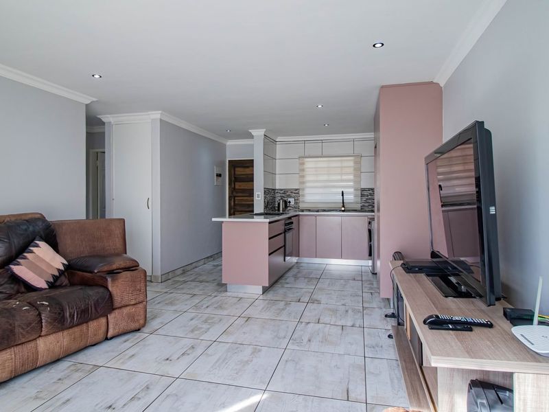 Open-plan living area featuring a modern kitchen with built-in cabinetry, a central island, and tiled flooring throughout the combined space.