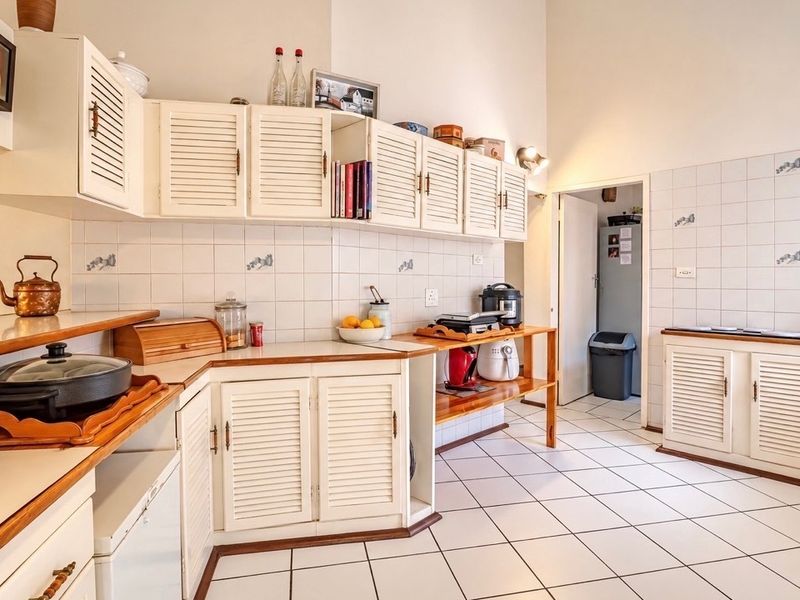 A functional kitchen featuring white louvered cabinetry, tiled backsplash, and wooden countertops, offering a classic layout with ample storage space.