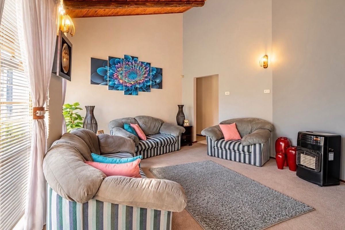 Spacious living room featuring exposed timber ceiling beams, wall sconce lighting, and a built-in gas heater, creating a warm and inviting atmosphere.