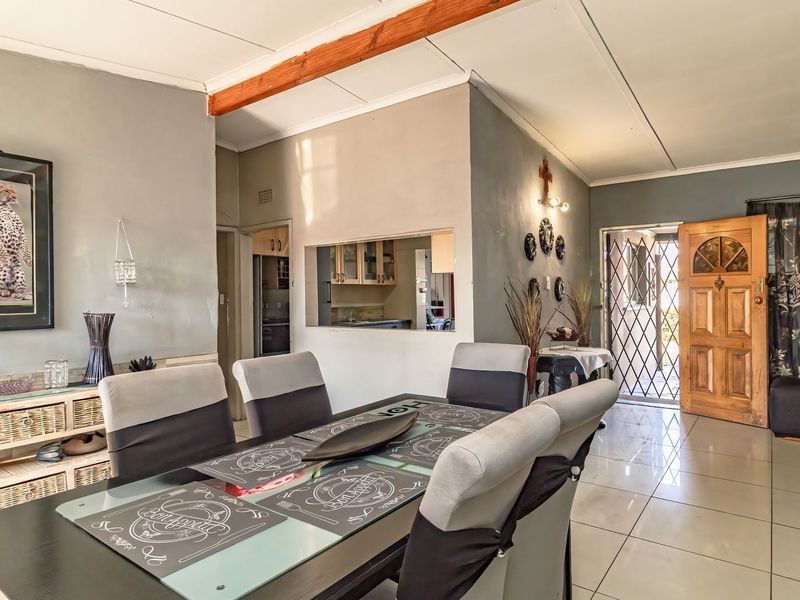 Open-plan dining area featuring tiled flooring, an exposed ceiling beam, and a convenient serving hatch connecting to the kitchen space.