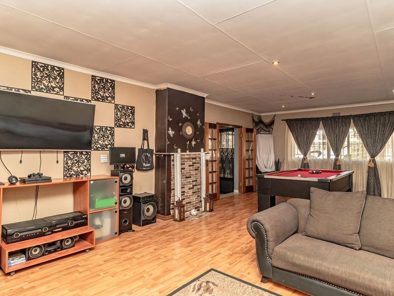 Spacious living room featuring laminate flooring, a central fireplace, and recessed lighting, offering a versatile area for relaxation and entertainment.