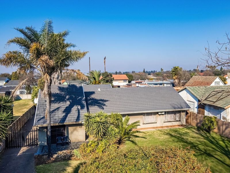 Aerial view of a residential property featuring a tiled roof, established garden, and driveway, situated in a suburban neighborhood.