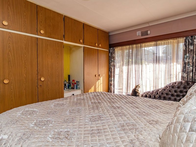 A bedroom featuring extensive built-in wooden cabinetry, an air conditioning unit, and large sliding glass doors providing natural light.