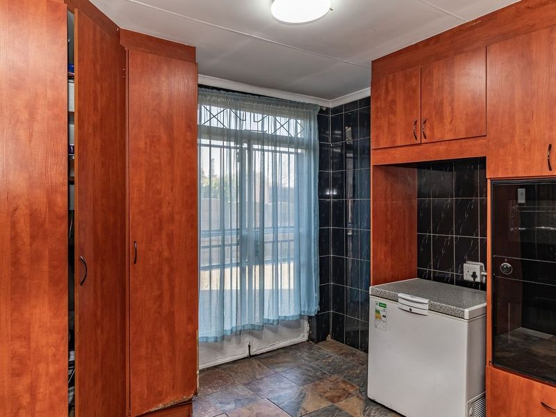 A functional scullery area featuring built-in wooden cabinetry, tiled splashbacks, and a built-in oven, providing convenient additional prep and storage space.
