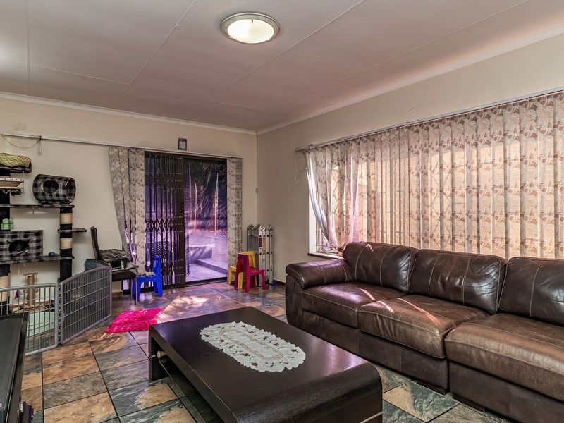 Spacious living room featuring tiled flooring, large windows with curtains, and a sliding glass door providing access to the exterior.