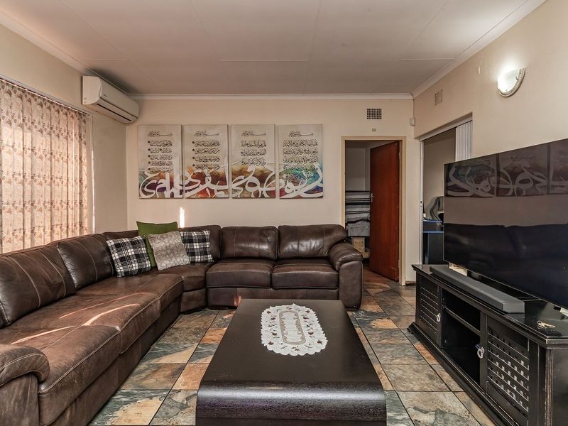 A comfortable living room featuring tiled flooring and a wall-mounted air conditioning unit, providing a functional and climate-controlled space.