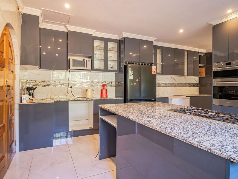Modern kitchen featuring granite countertops, gloss cabinetry, built-in oven, gas hob, and mosaic tile backsplash with recessed lighting throughout.