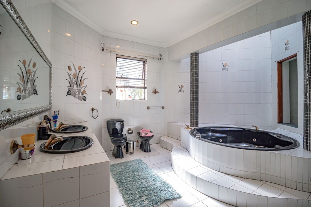 Spacious bathroom featuring a built-in sunken bathtub, dual vanity sinks, and tiled finishes throughout.