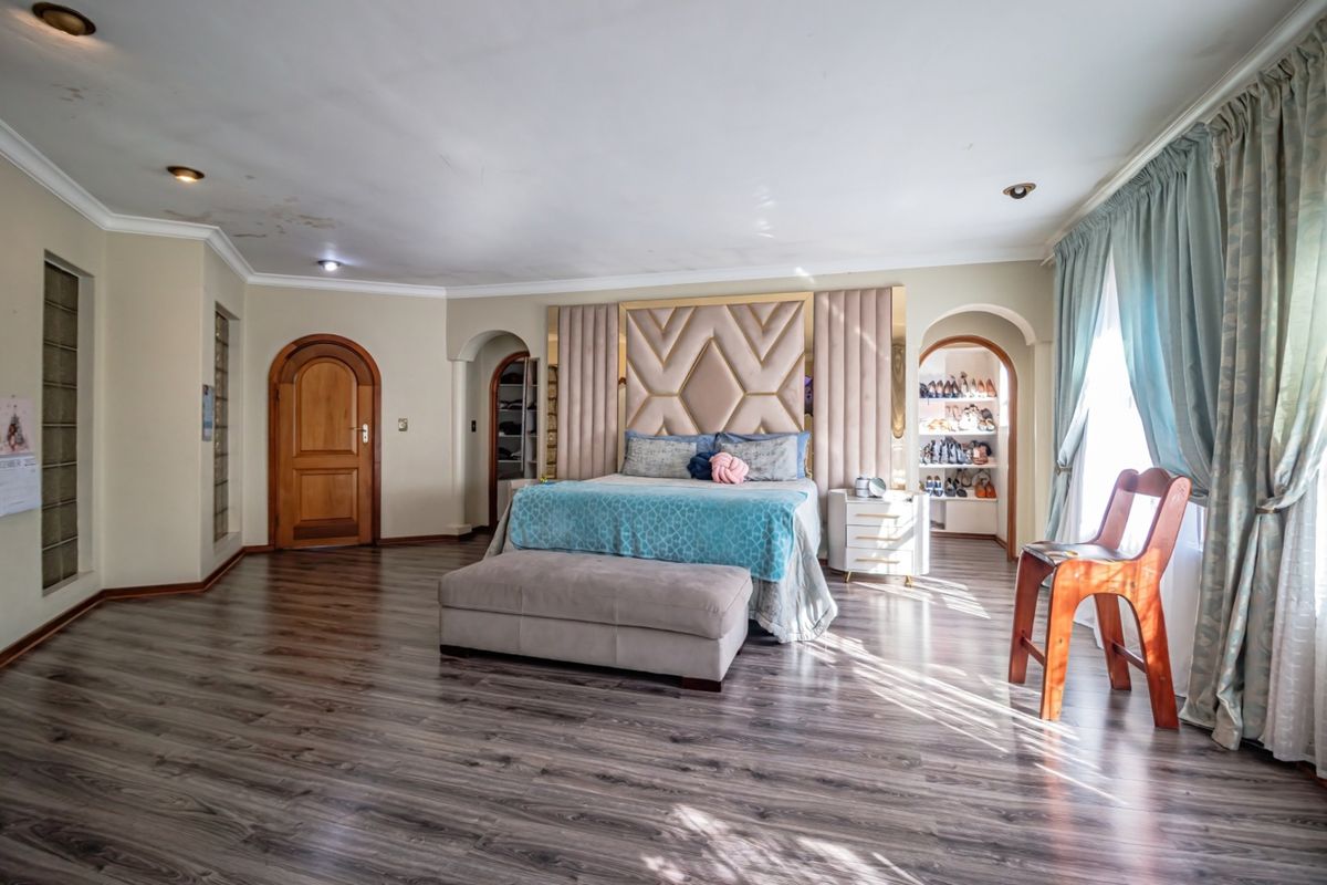 Spacious bedroom featuring laminate flooring, recessed lighting, and built-in storage alcoves with an integrated headboard design.