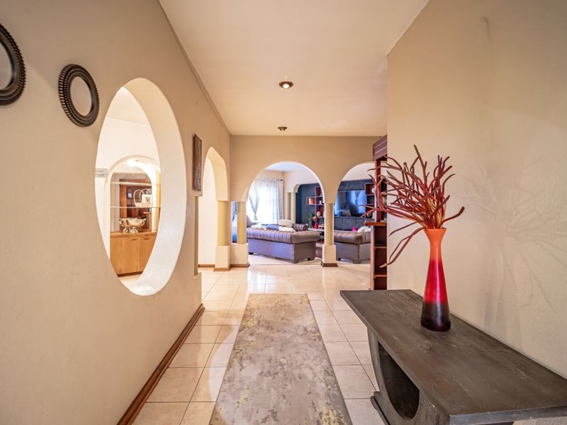 A spacious hallway featuring tiled flooring, distinctive circular wall cutouts, and elegant archways leading into the main living area.