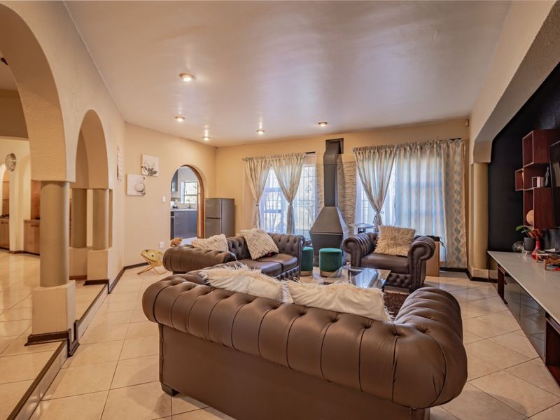 Spacious living room featuring tiled flooring, a central freestanding fireplace, and architectural archways leading to adjacent areas.