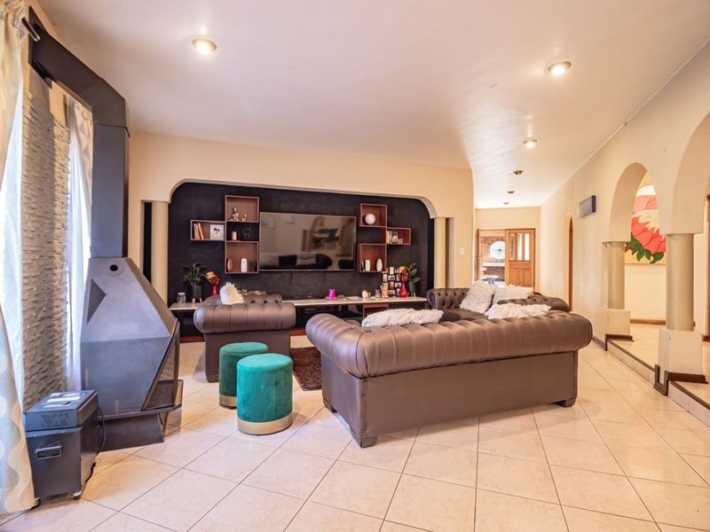 Spacious living room featuring a modern freestanding fireplace, tiled flooring, and distinctive arched architectural details leading to adjacent areas.