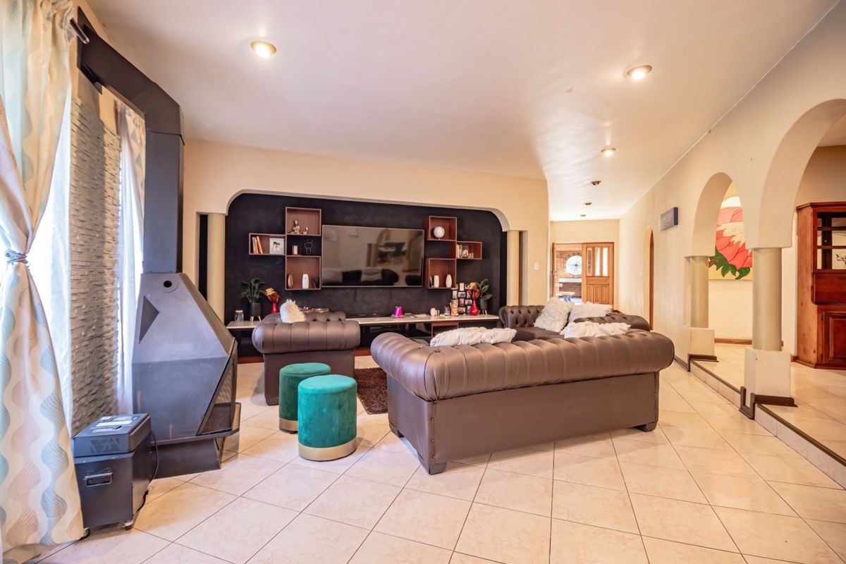 Spacious living room featuring a modern freestanding fireplace, tiled flooring, and distinctive arched architectural details leading to adjacent areas.
