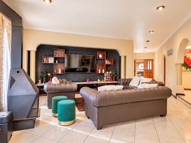 Spacious living room featuring a modern freestanding fireplace, tiled flooring, recessed lighting, and an elegant arched entryway leading to adjacent living spaces.