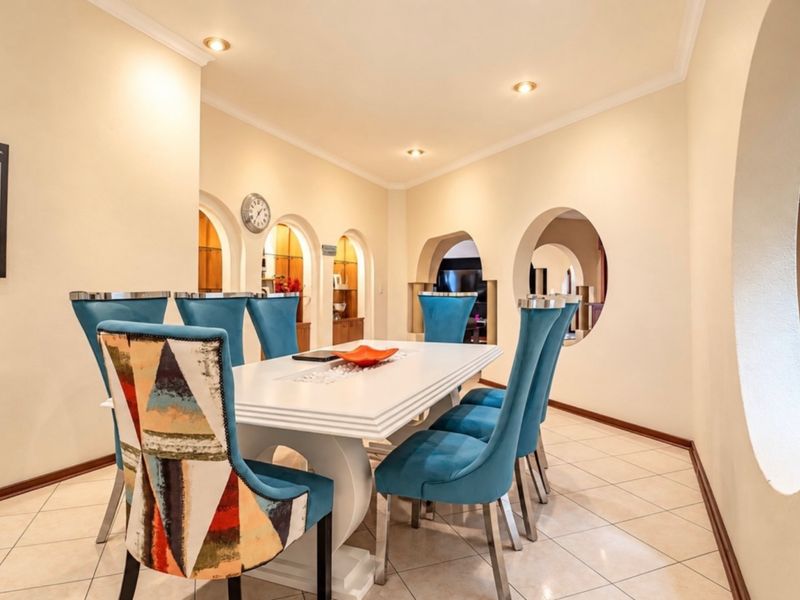 A well-lit dining room featuring unique architectural archways, a circular wall cutout, and neutral tiled flooring, creating a distinct and open atmosphere.
