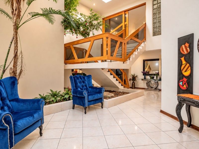 Spacious entrance hall featuring a prominent wooden staircase, tiled flooring, a skylight, and a unique indoor planter bed.