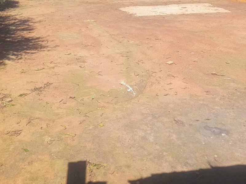 A vacant residential plot featuring an open dirt area with a small concrete slab and perimeter fencing.