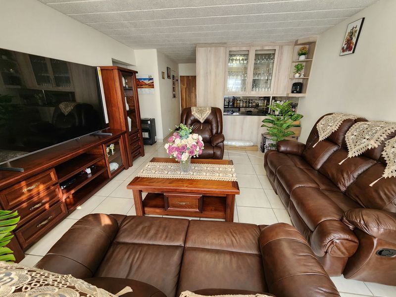A comfortable living room featuring tiled flooring and integrated built-in cabinetry with glass-fronted display units, providing ample storage and a functional layout.