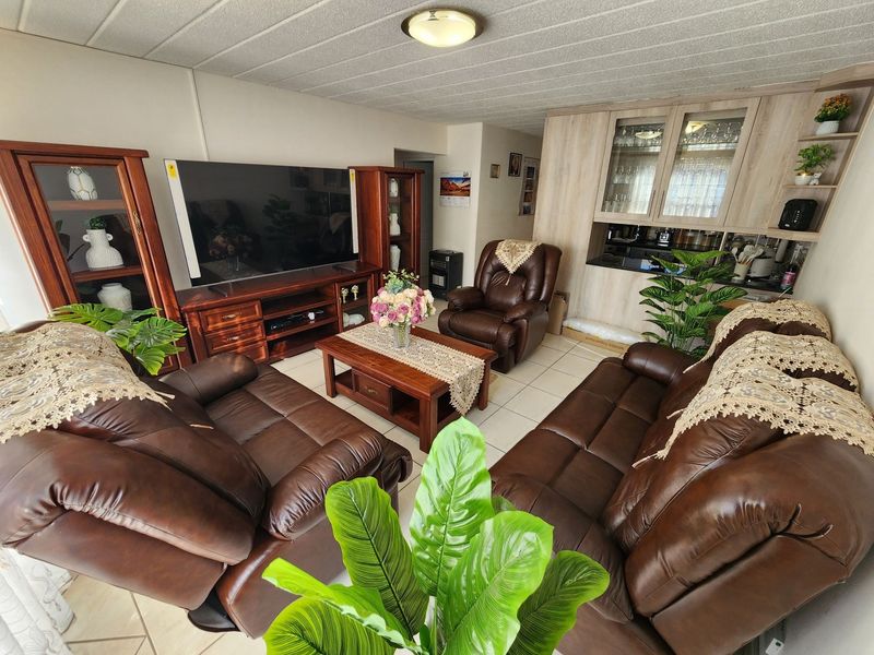 Open plan living area featuring tiled flooring and integrated cabinetry with glass display sections, providing a functional and connected living and storage space.