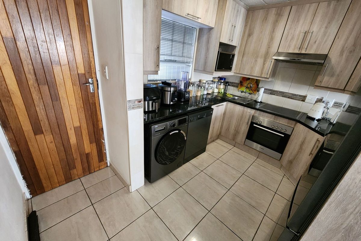 A functional kitchen featuring light wood-finish cabinetry, granite countertops, integrated appliances, and tiled flooring, providing a practical and well-maintained cooking space.
