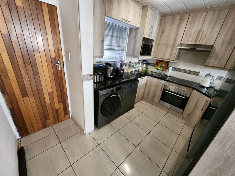 A functional kitchen featuring light wood-finish cabinetry, granite countertops, integrated appliances, and tiled flooring, providing a practical and well-maintained cooking space.
