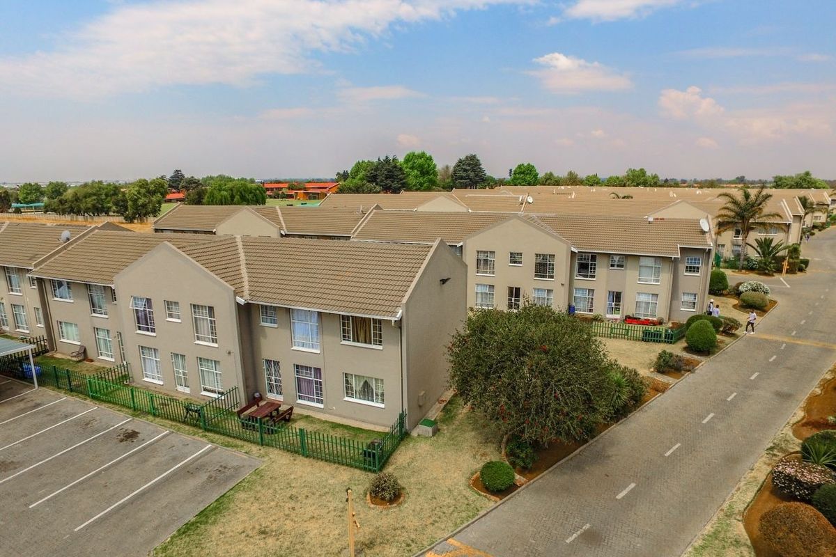 Aerial view of a residential apartment complex featuring multiple units with tiled roofs, paved parking areas, and landscaped grounds.
