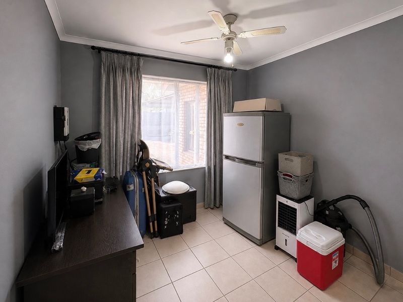 A functional utility space featuring tiled flooring and a ceiling fan, currently utilized for storage and general household utility purposes.