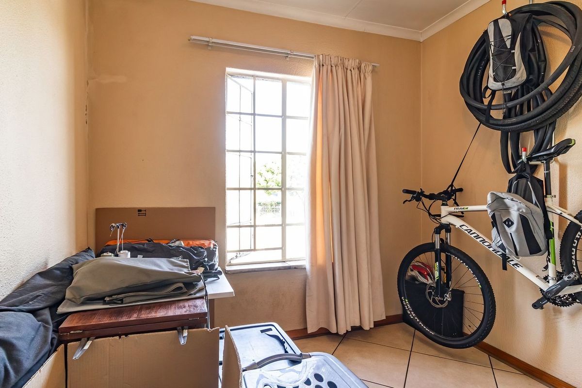 A compact bedroom featuring tiled flooring and a window with security bars, currently utilized as a storage space.