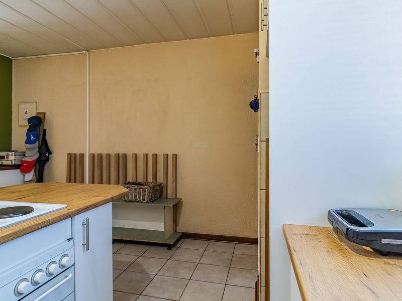A functional kitchen area featuring a built-in electric hob, oven, and wooden countertops, with tiled flooring and neutral wall finishes.