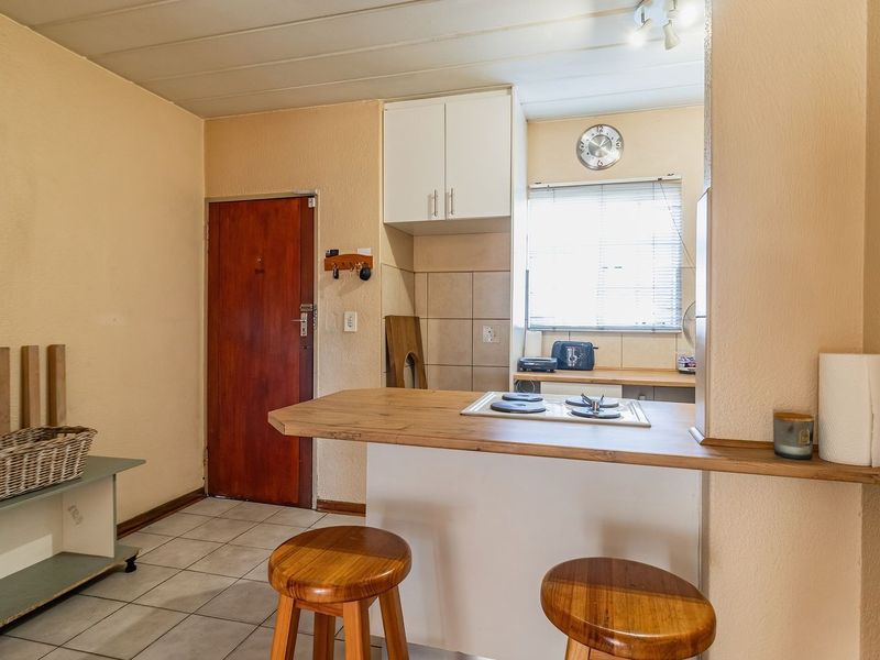 Open plan kitchen area featuring a breakfast bar, built-in hob, and tiled flooring, providing a functional space for cooking and casual dining.