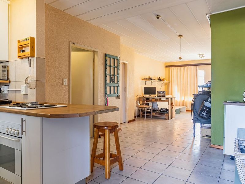 Open-plan kitchen and living area featuring tiled flooring, built-in oven, gas hob, and timber countertop, offering a functional layout for modern living.
