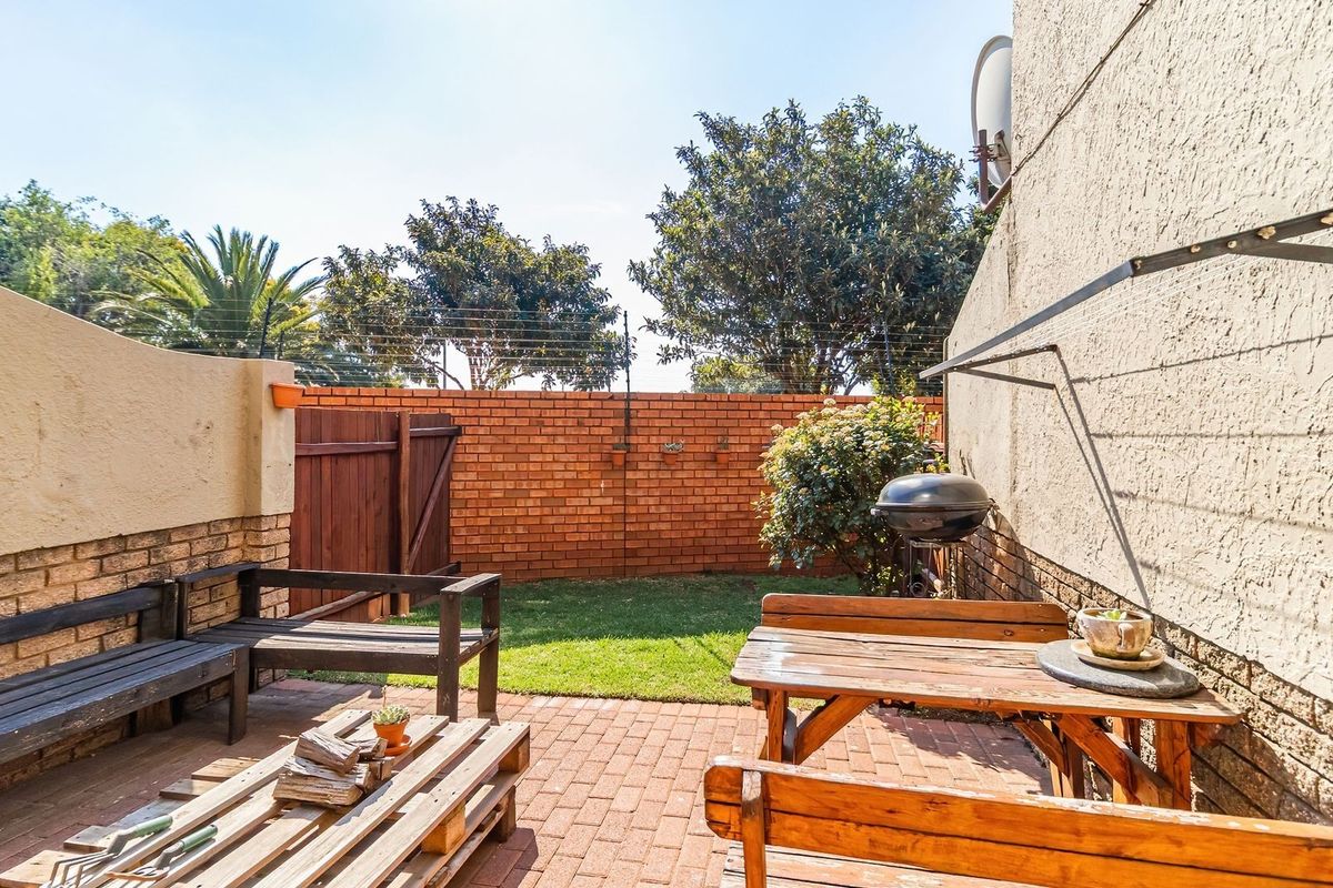 A private rear courtyard featuring a paved patio area, brick boundary walls with electric fencing, and a wall-mounted washing line.