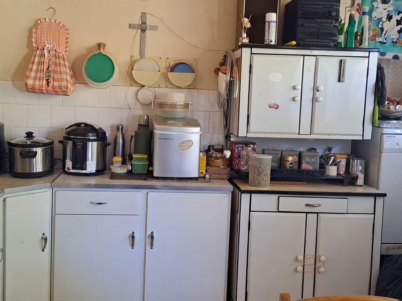 A functional kitchen featuring white built-in cabinetry, laminate countertops, and a tiled splashback, offering potential for modernization and aesthetic updates.