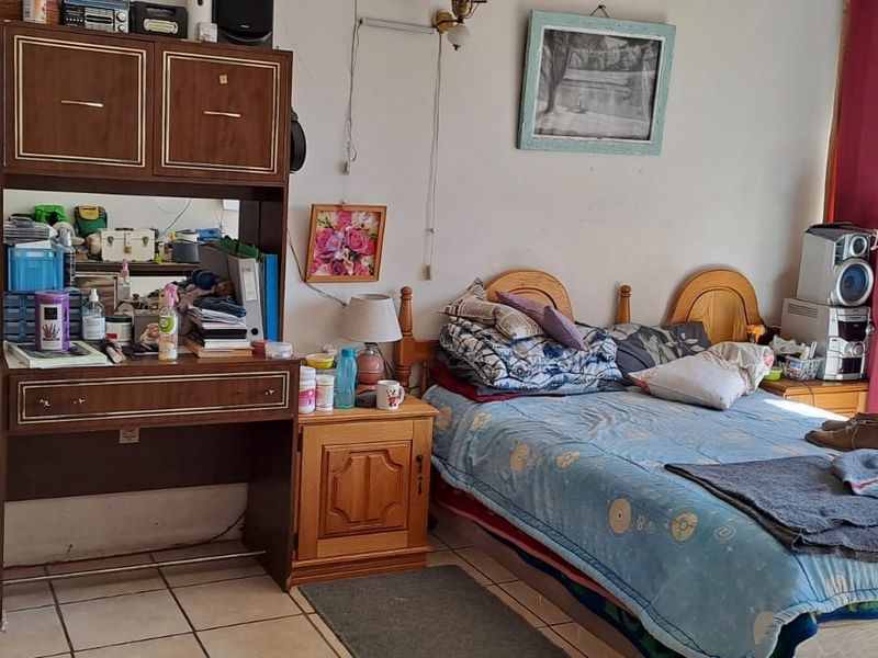 A bedroom featuring tiled flooring and a sliding glass door with security gate, providing access to the exterior.
