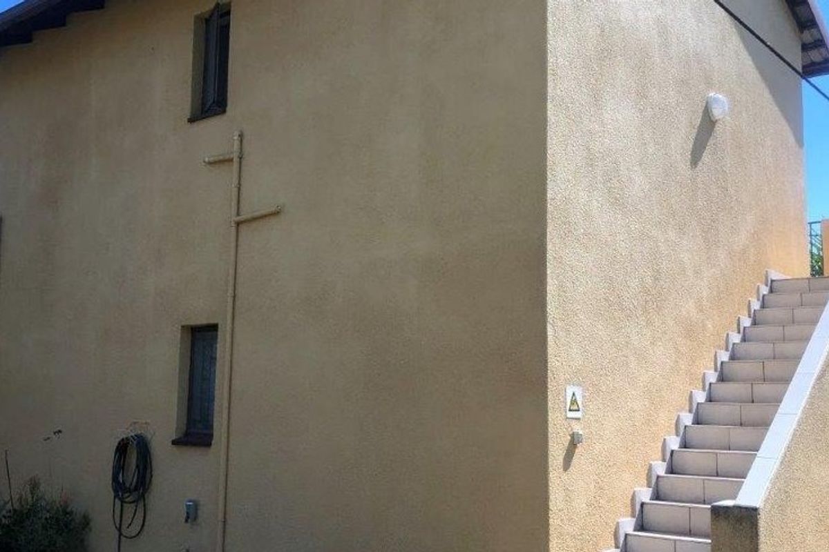 Rear exterior view of the property featuring a rendered facade and an external staircase with tiled steps.