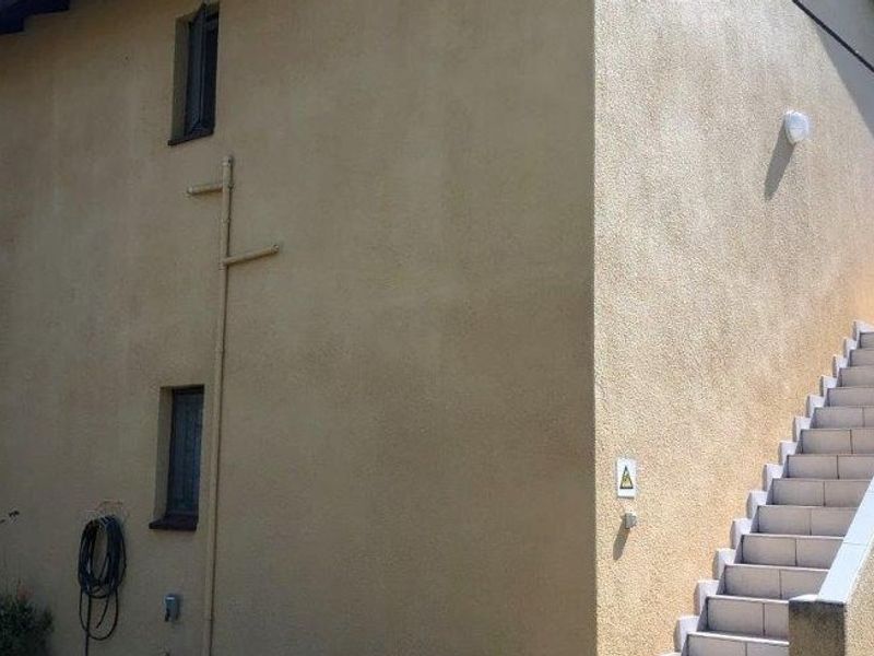 Rear exterior view of the property featuring a rendered facade and an external staircase with tiled steps.