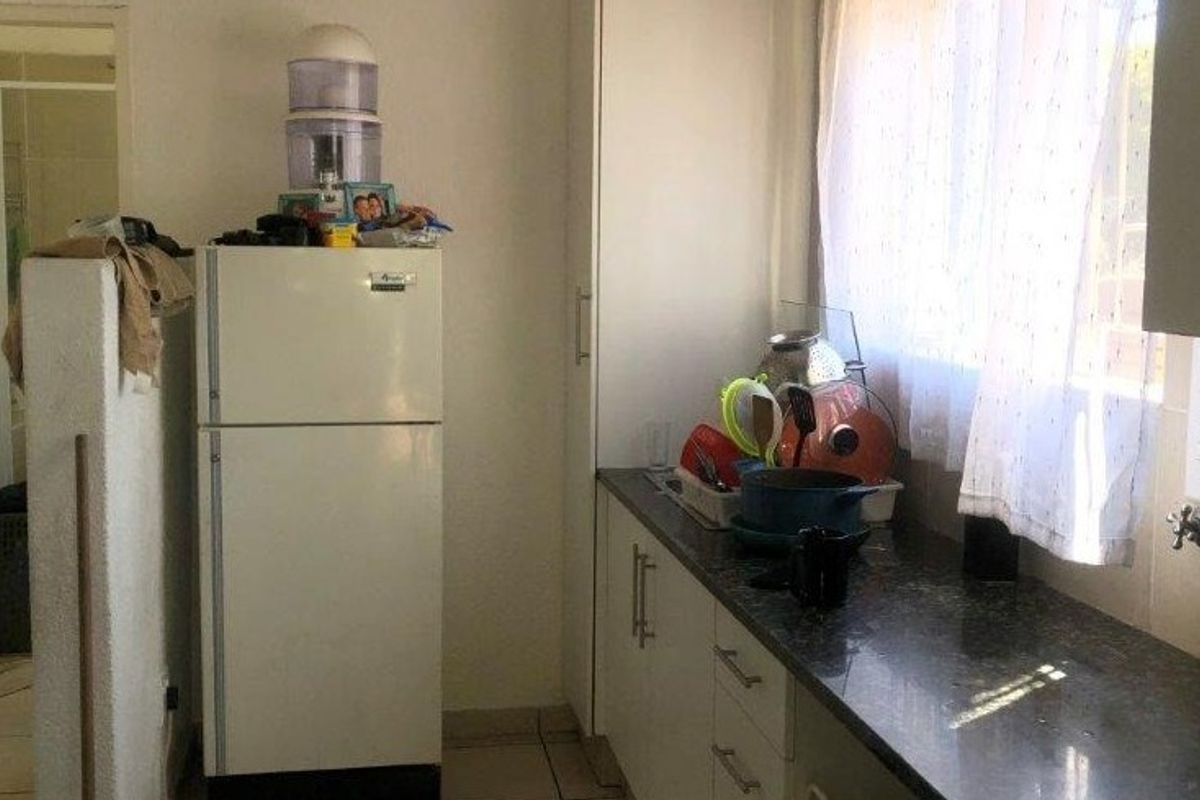 A functional kitchen area featuring granite countertops, built-in cabinetry, and tiled flooring, providing a practical workspace for daily culinary activities.