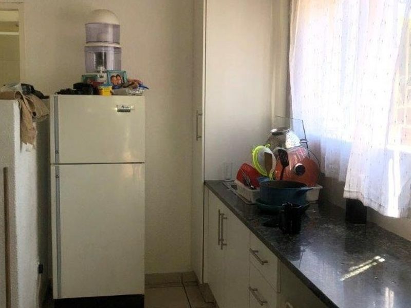 A functional kitchen area featuring granite countertops, built-in cabinetry, and tiled flooring, providing a practical workspace for daily culinary activities.