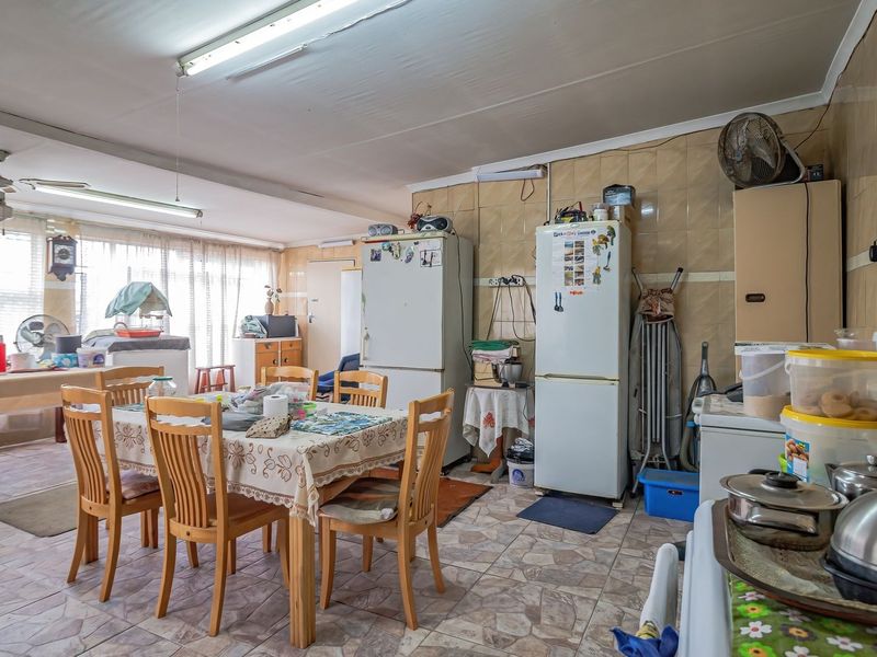 Spacious open-plan kitchen and dining area featuring tiled flooring and wall finishes, offering a functional layout with potential for modern updates.