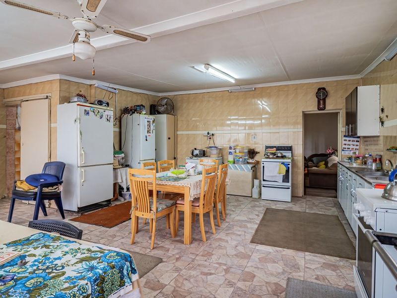 A spacious, dated kitchen featuring tiled walls and floors, equipped with a freestanding stove and ample cabinetry, offering significant potential for a modern renovation.