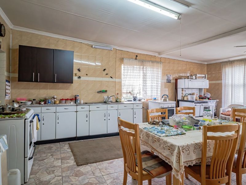 Spacious kitchen featuring extensive built-in cabinetry, tiled splashbacks, and a functional layout with ample space for a dining area.