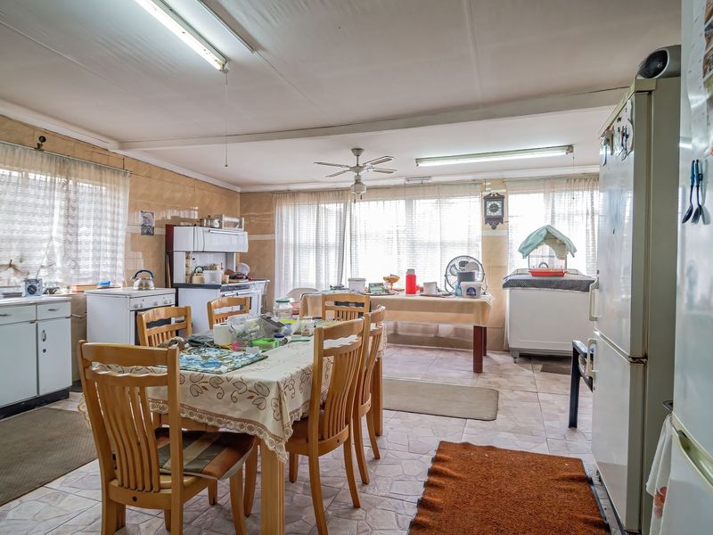Spacious open-plan kitchen and dining area featuring tiled flooring, built-in cabinetry, and a functional layout ready for modernization.