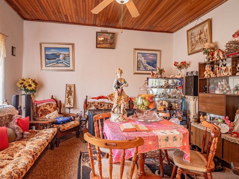 A living room featuring a timber-clad ceiling and a central ceiling fan, offering a traditional aesthetic with potential for modernization.